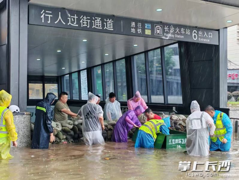 五里牌街道应急分队、辖区单位中铁十八局争分夺秒搬运沙袋，迅速在火车站地铁6号出入口前筑起一道坚固的防线。  受访方供图